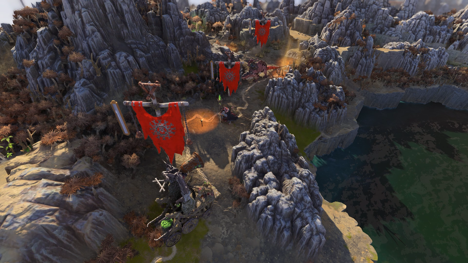The camera looks down on a procession of skaven troops trudging single file through a rocky outcrop, their large red banners held aloft.